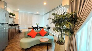 A modern living room with a curved sofa, a small round table, and a potted plant. - Dinh Ami Hanoi Hotel (Hanoi)
