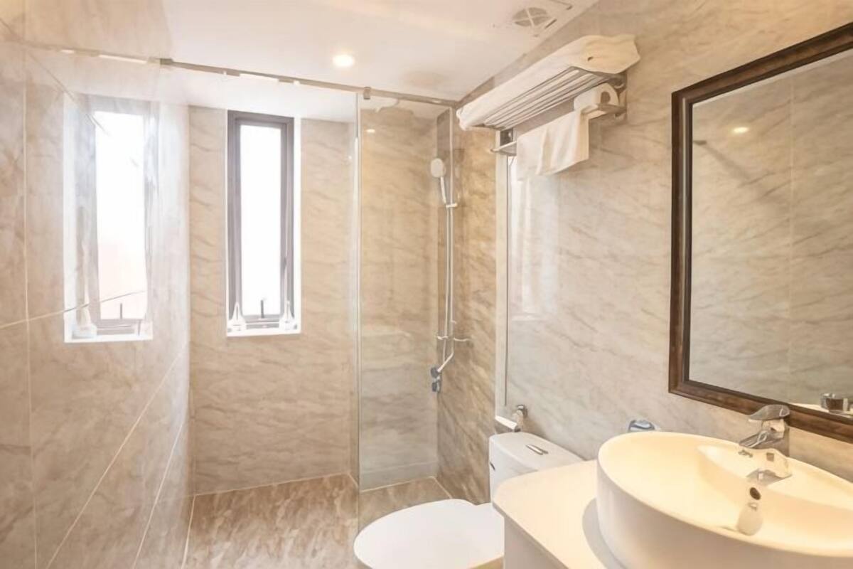 Une salle de bain moderne dotée d’une douche à parois de verre, de toilettes et d’un lavabo avec un grand miroir.