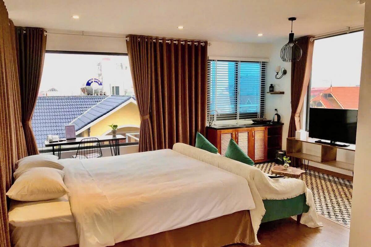 Une chambre d’hôtel avec un grand lit, une table à manger, un téléviseur et une vue sur le paysage urbain.