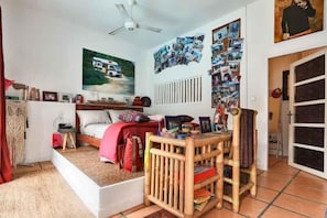 Un dormitorio acogedor con una cama, una pequeña mesa de madera y una pared decorada con fotografías y un cuadro.