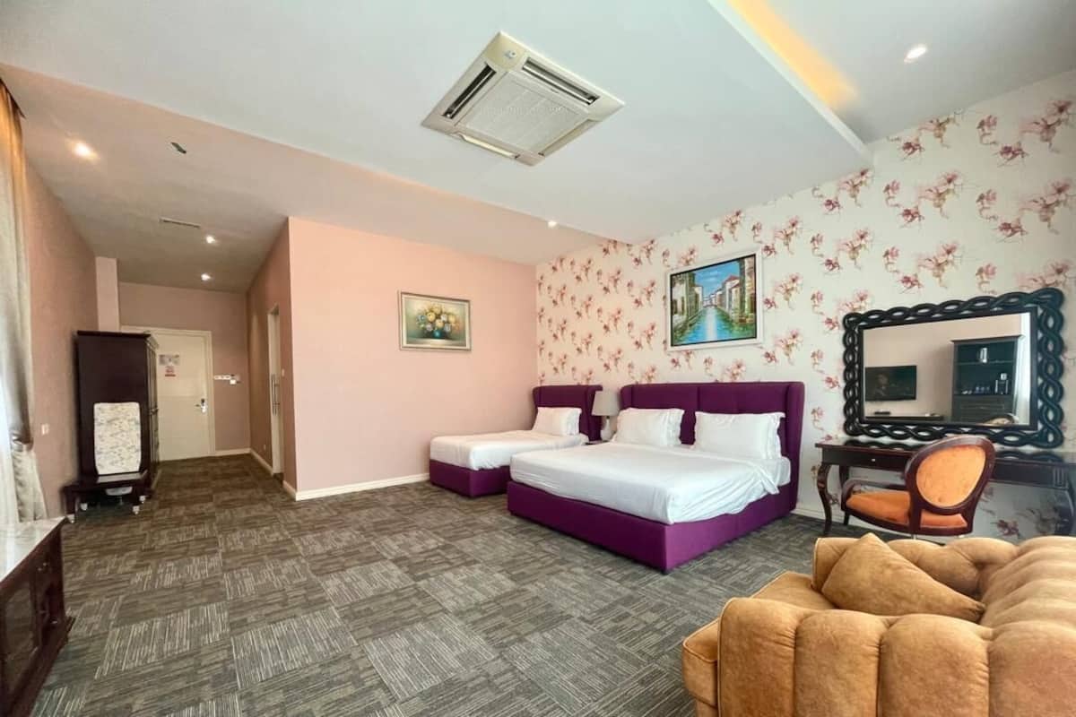 A hotel room with a bed, a sofa, a desk, and a mirror.
