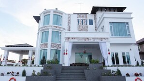 Una casa moderna de dos pisos con fachada curva, ventanas amplias y una entrada central con escalones.