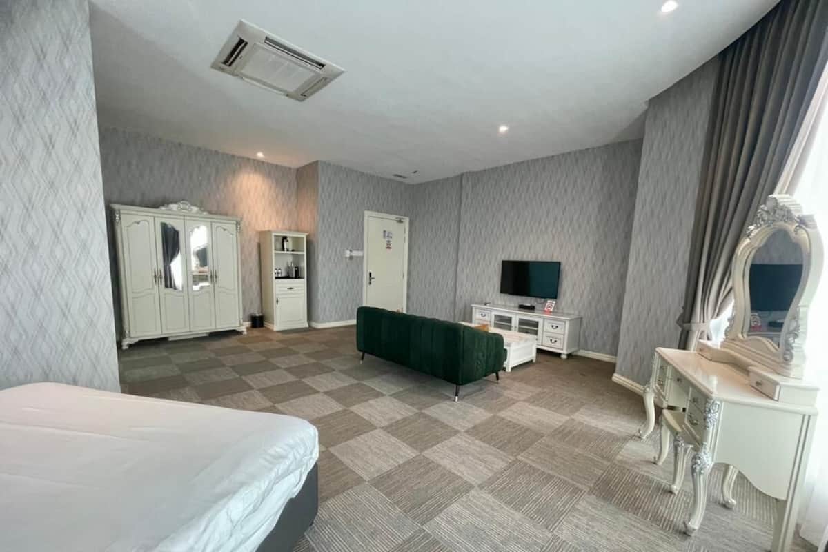 A hotel room with a bed, wardrobe, vanity, and a television.