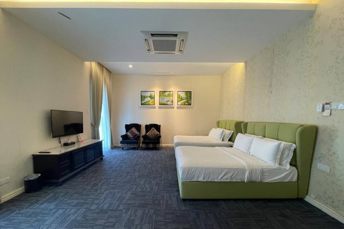 A hotel room with a large bed, a TV, a small seating area, and a carpeted floor.