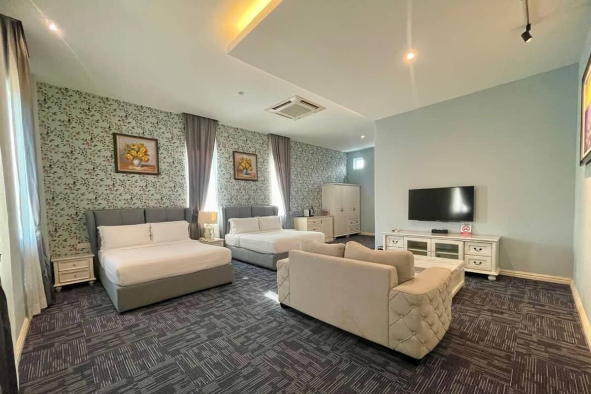A hotel room with a bed, two sofas, a TV, and a wardrobe.