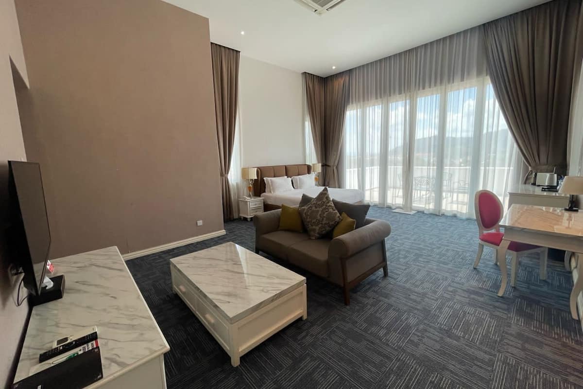 A hotel room with a bed, a sofa, a coffee table, a TV, and a desk with a chair.