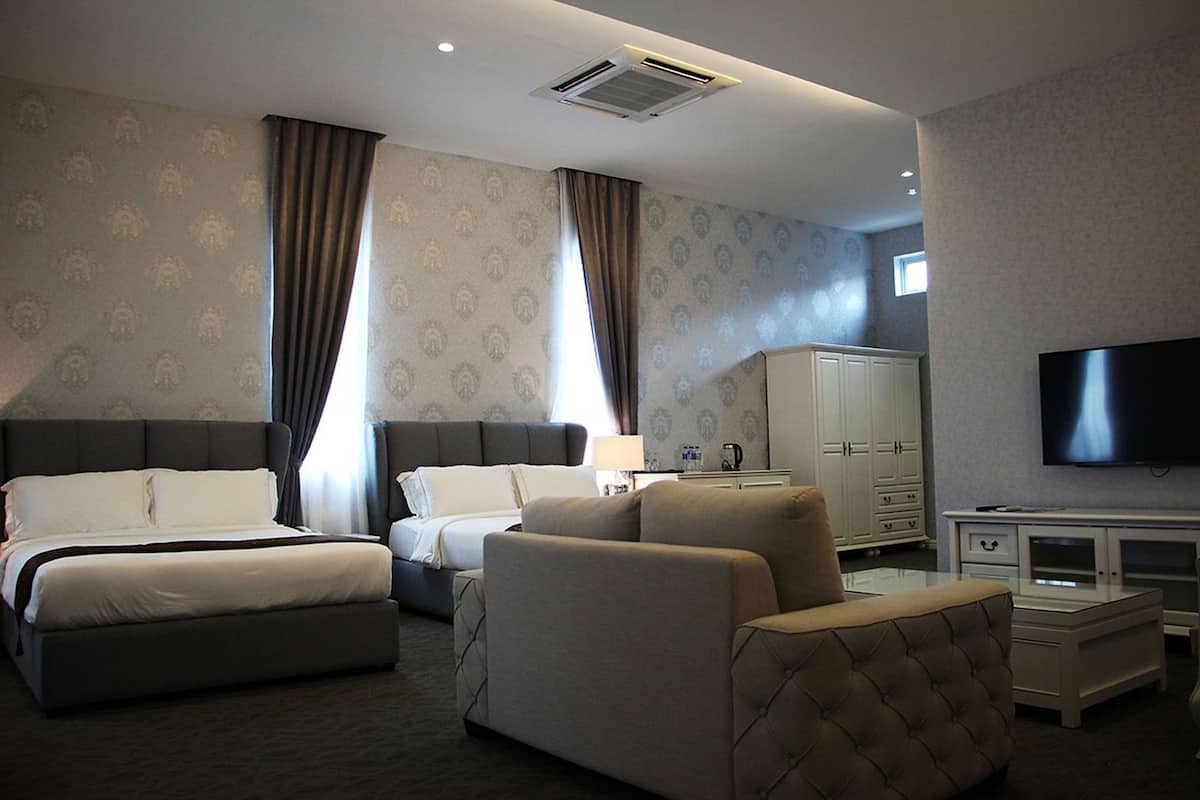 A hotel room with a bed, two sofas, a TV, a cabinet, and a desk.