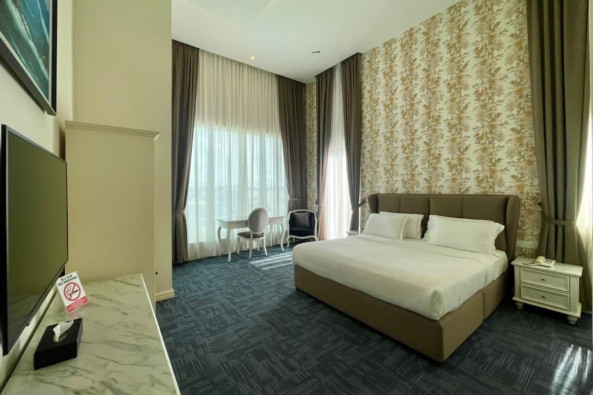 A hotel room with a bed, a desk, a chair, a TV, and a nightstand.