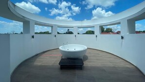 Un baño moderno con una bañera independiente, ventanas amplias y un techo curvo.