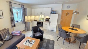 A compact living space with a kitchenette, a dining area, and a sofa with a coffee table.