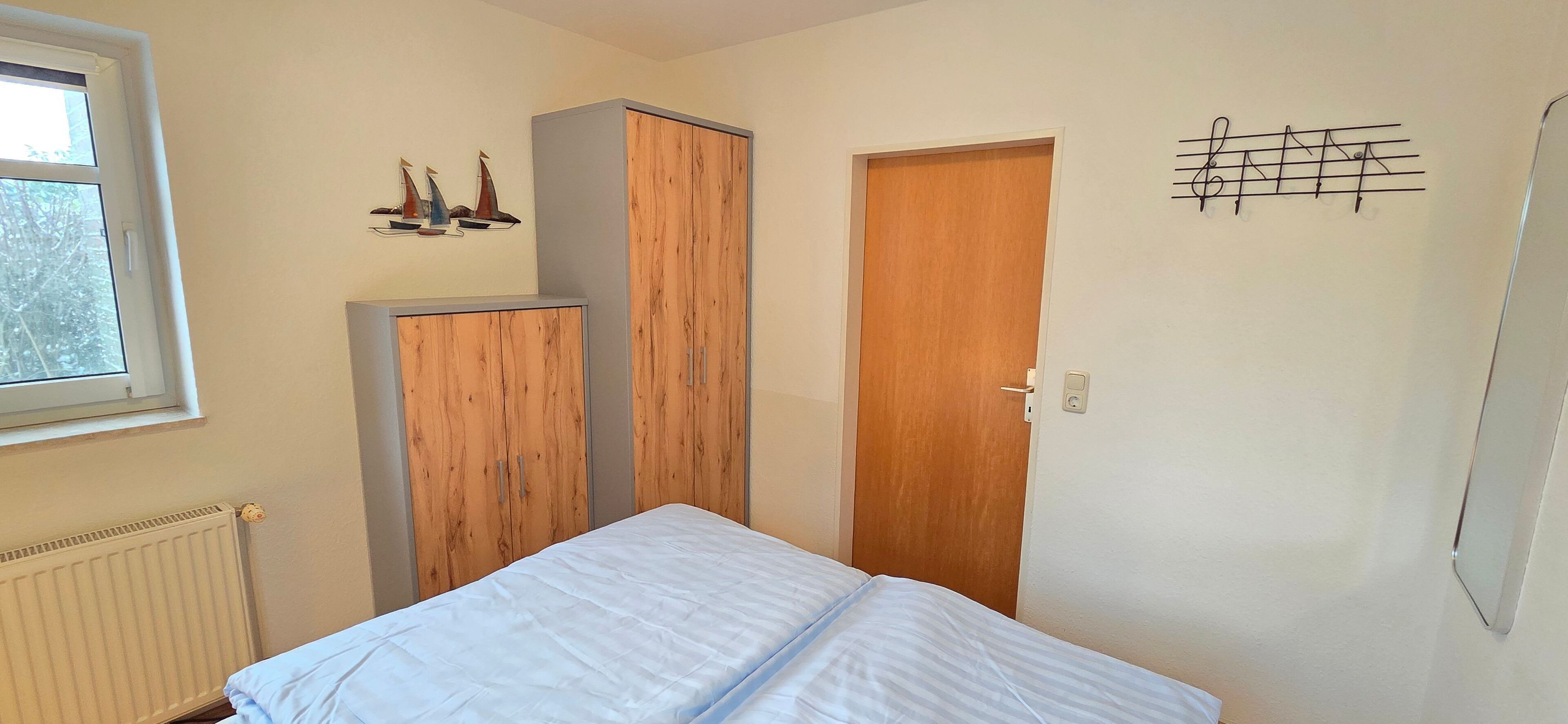 Un dormitorio con cama, armario, puerta y ventana.