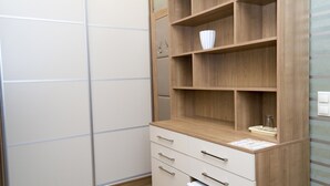 Un baño moderno con tocador de madera, un armario blanco y pared de azulejos.