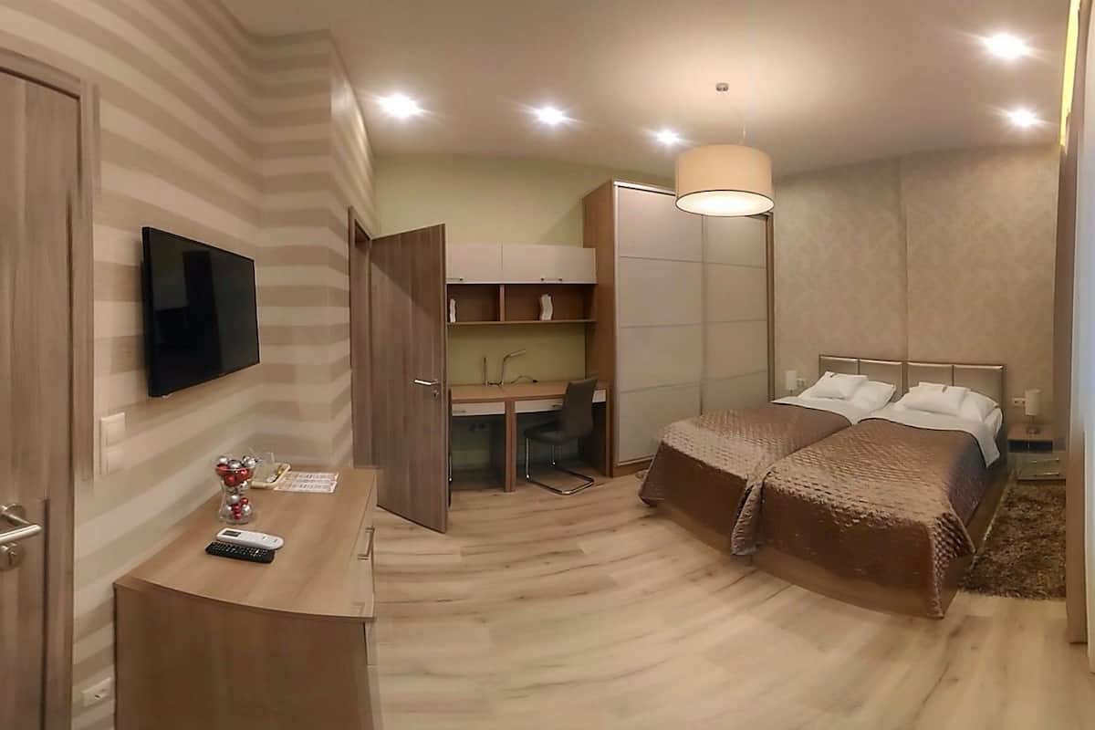 A modern hotel room with a bed, desk, and TV.
