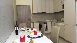 Comedor con una mesa preparada para dos personas, una botella de vino y un microondas al fondo.