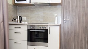 Una cocina con horno empotrado, microondas y hervidor en la encimera.