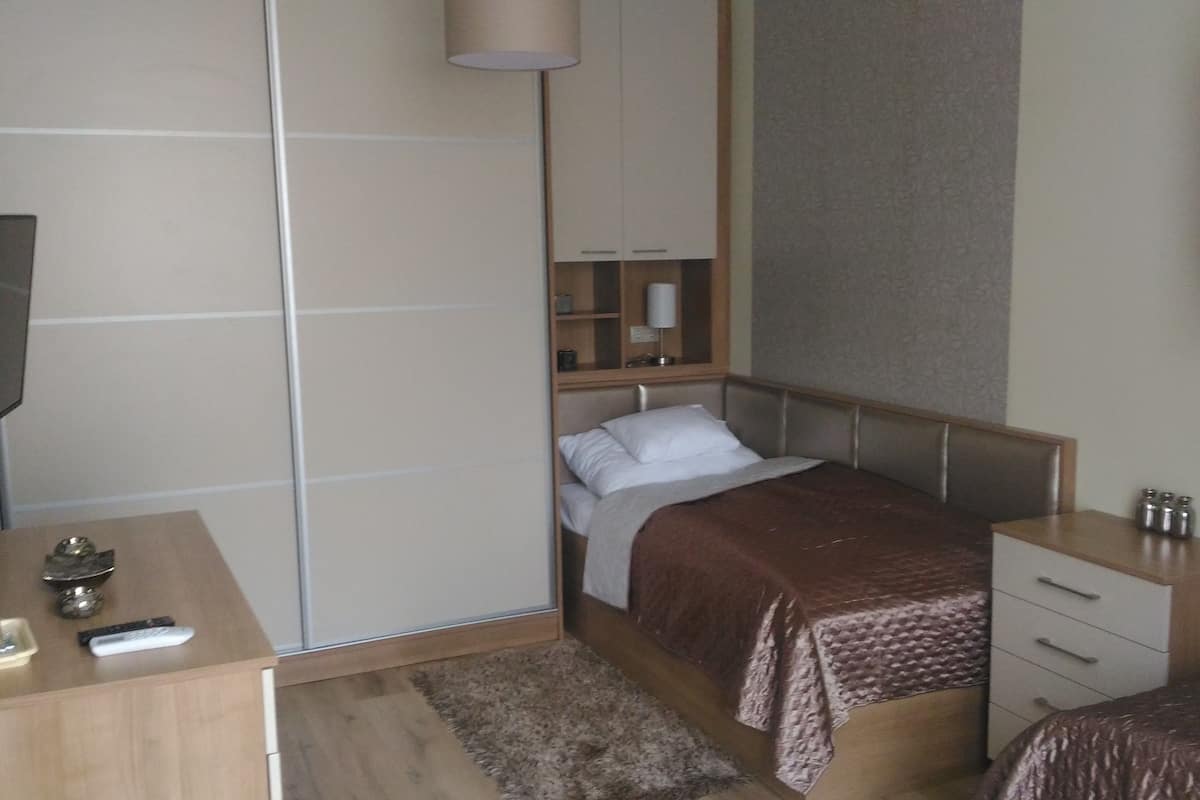 A bedroom with a bed, bedside tables, a desk, a TV, and a wardrobe.