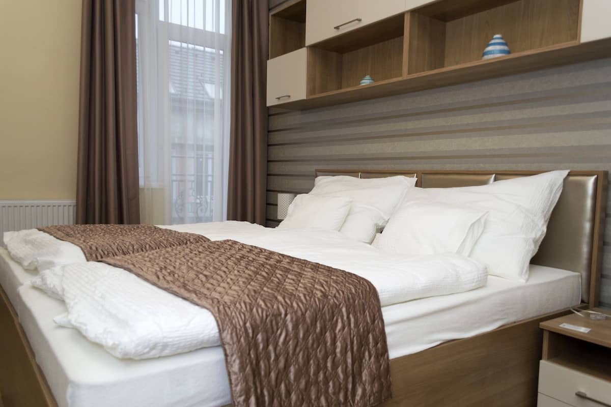 A neatly made bed with a brown blanket, a wooden headboard, and a bedside table with a lamp.