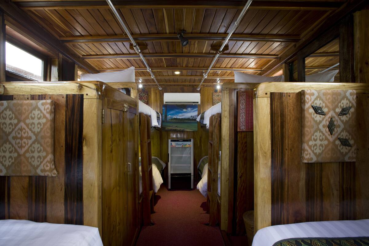 Un couloir étroit aux murs en bois et au sol recouvert d’une moquette, qui mène à une porte au fond.