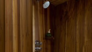 A wooden interior with a shower area, a soap dispenser, and a metal sign. - Plataran Phinisi Waecicu (Labuan Bajo)