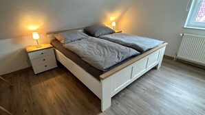 Ett sovrum med en säng, sängbord och ett fönster.