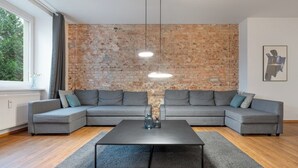 Una sala moderna con un sofá modular, una mesa de centro y una pared de ladrillo.