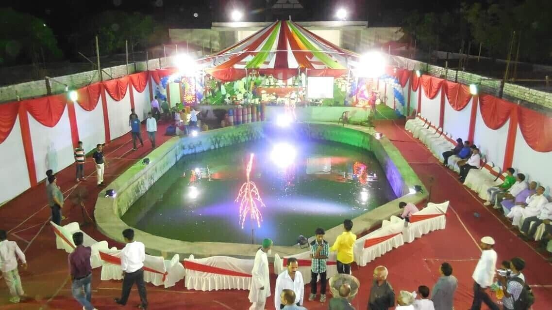 A large indoor event with a stage, seating, and a central water feature.