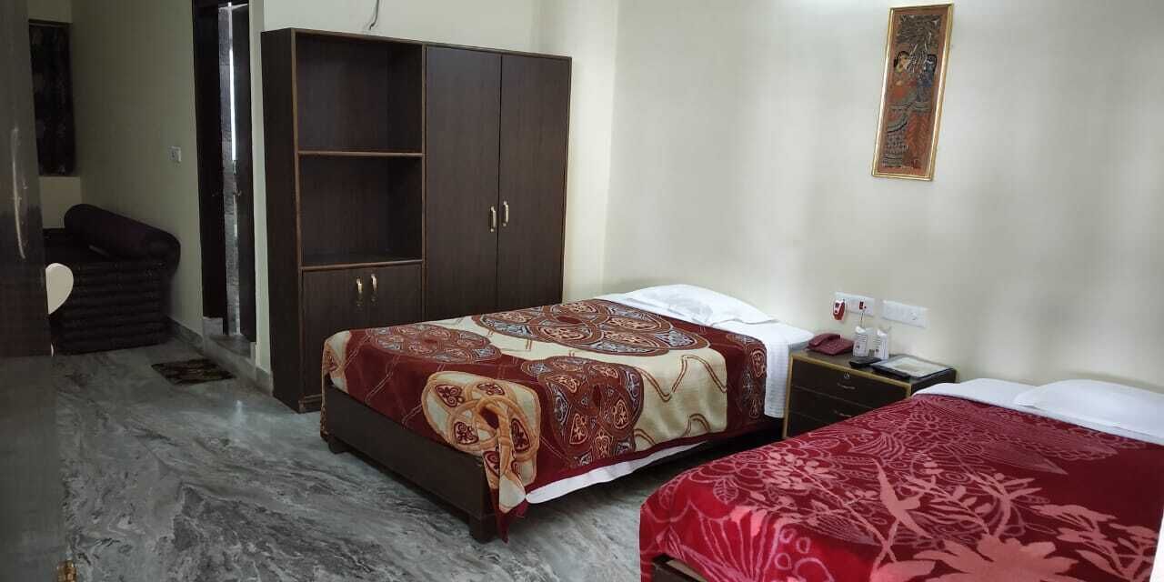 A hotel room with a bed, a wardrobe, a desk with a telephone, and a chair.