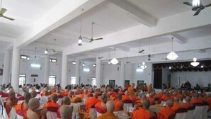 A large hall with rows of tables and chairs, where people are seated and engaged in an event.