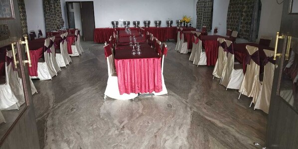 A conference room with multiple tables, each covered with a red tablecloth and white chairs.