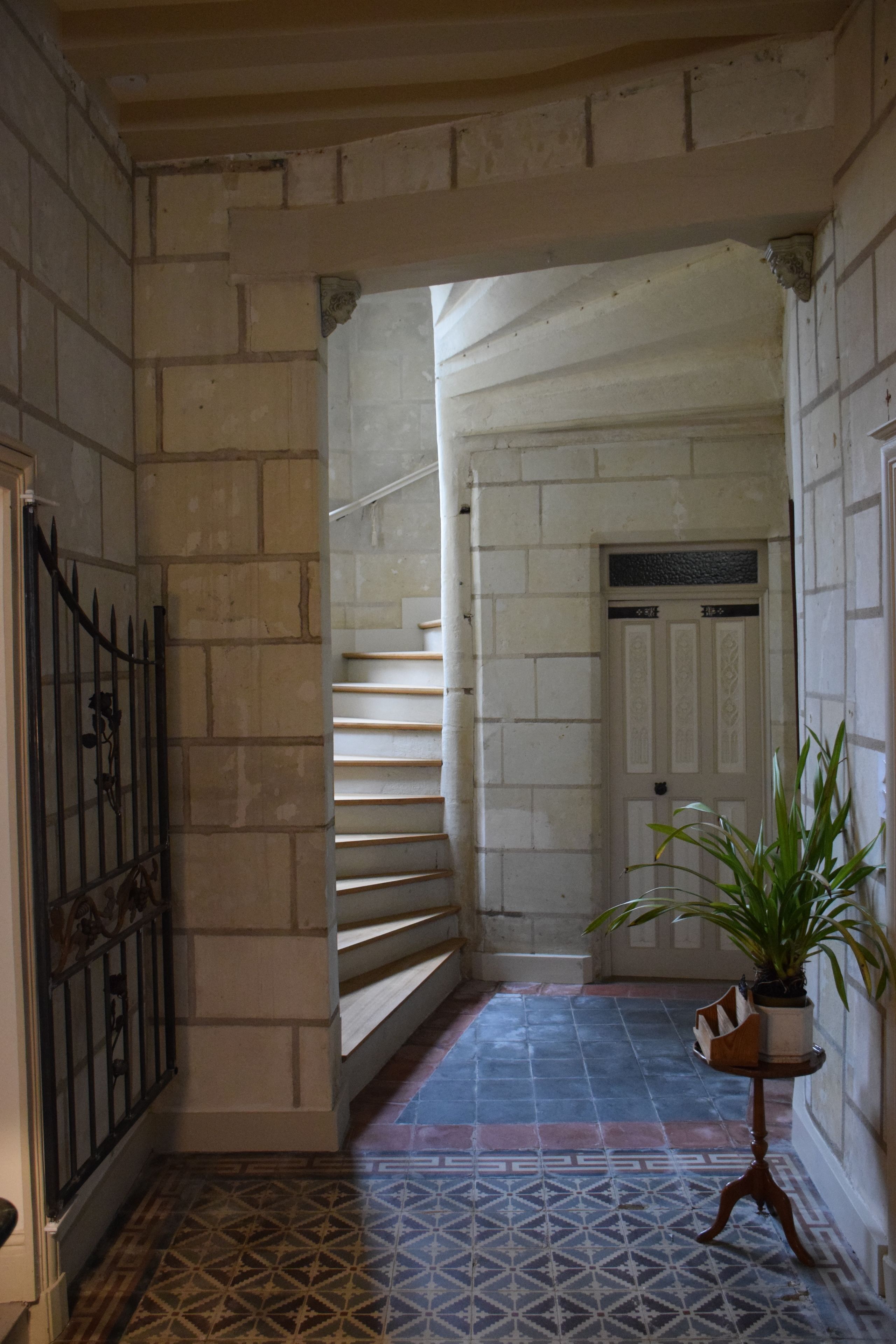 A hallway with a patterned floor, a staircase, and a door at the end.