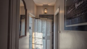 A hallway with wooden flooring, white walls, and a door with decorative glass panels. - Au Relais Saint Maurice (Chinon)