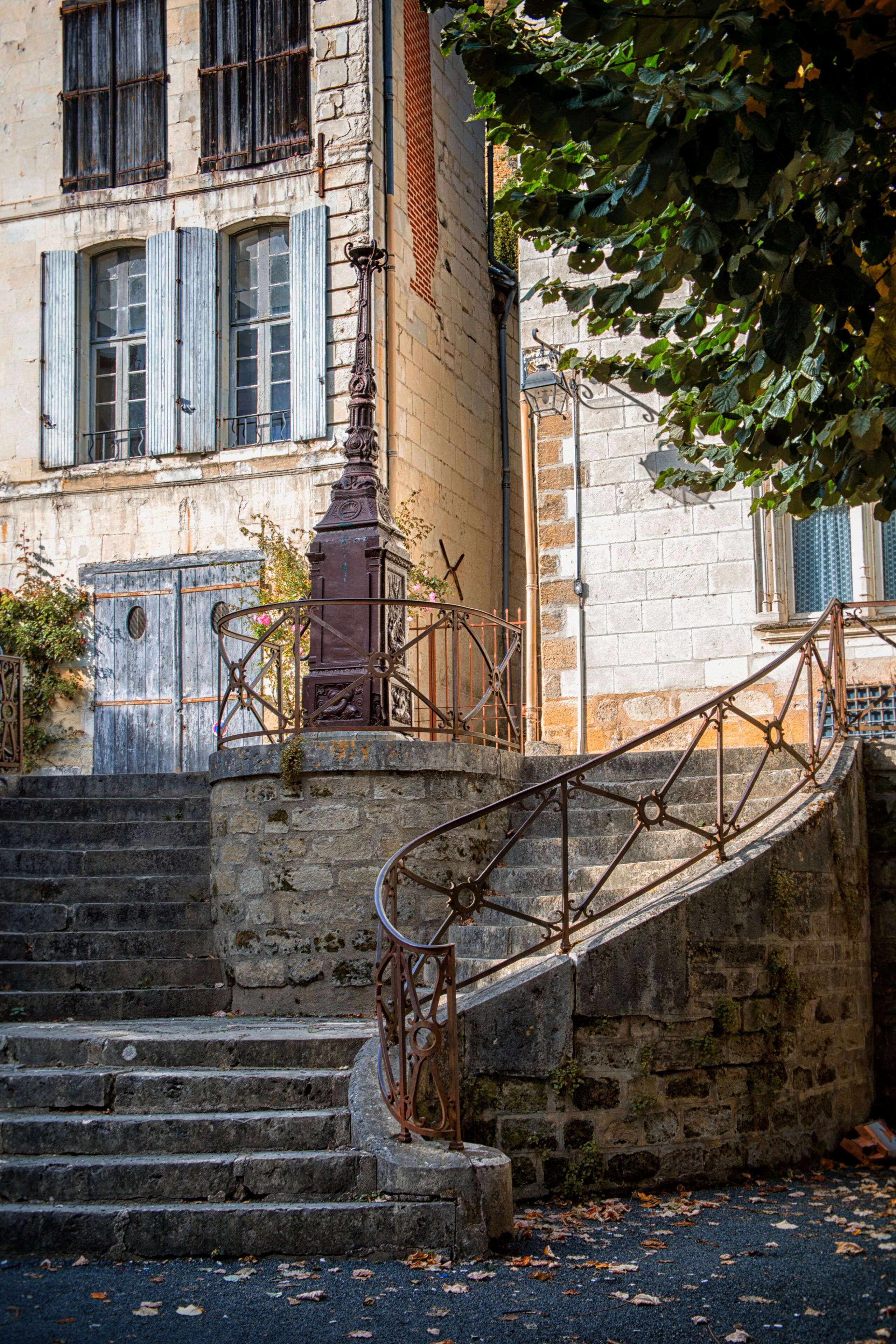 A stone staircase with metal railings leading to a building with blue shutters and a decorative metal railing.