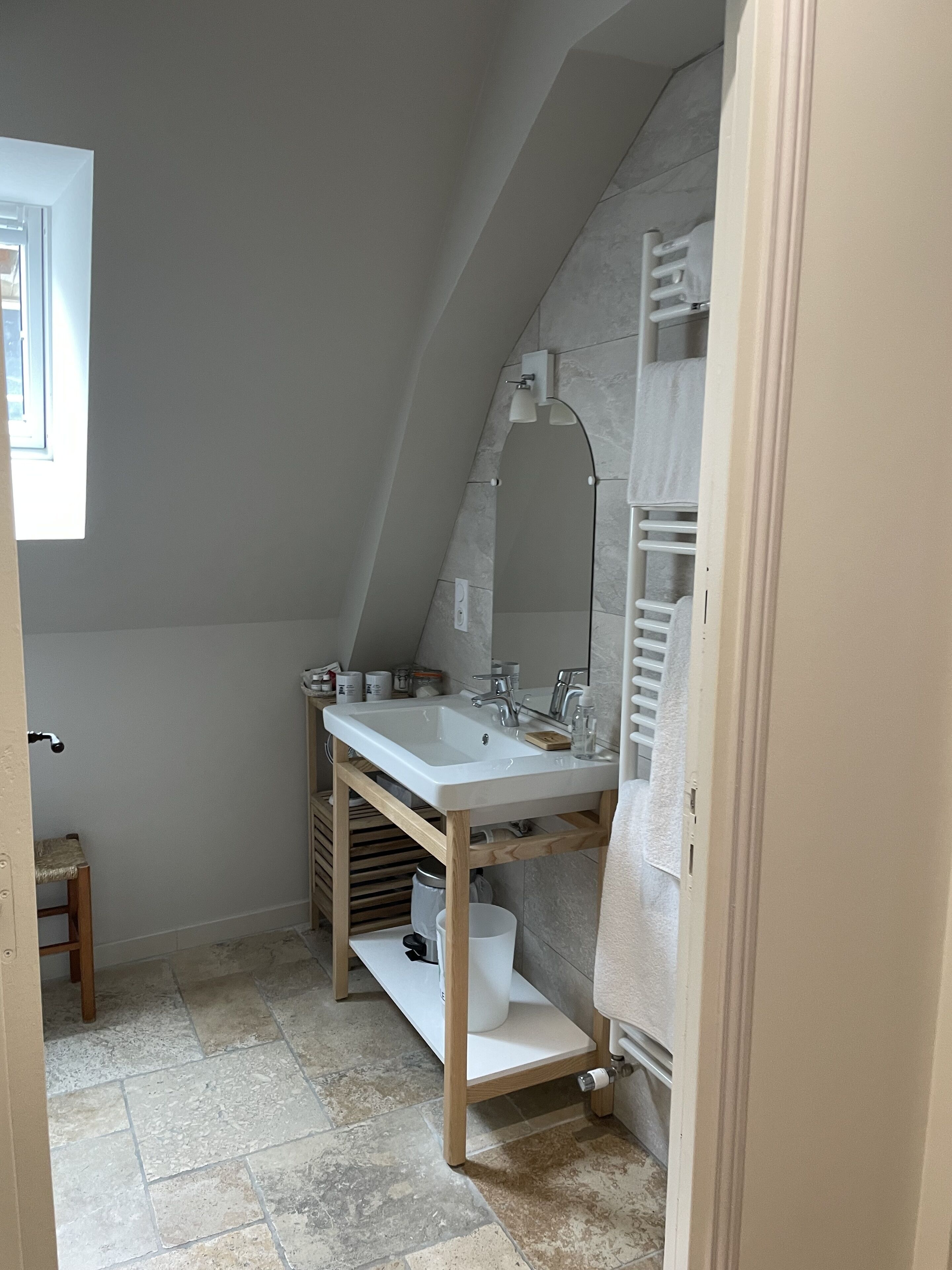 A small, modern bathroom with a sloped ceiling, a white sink, and a mirror.