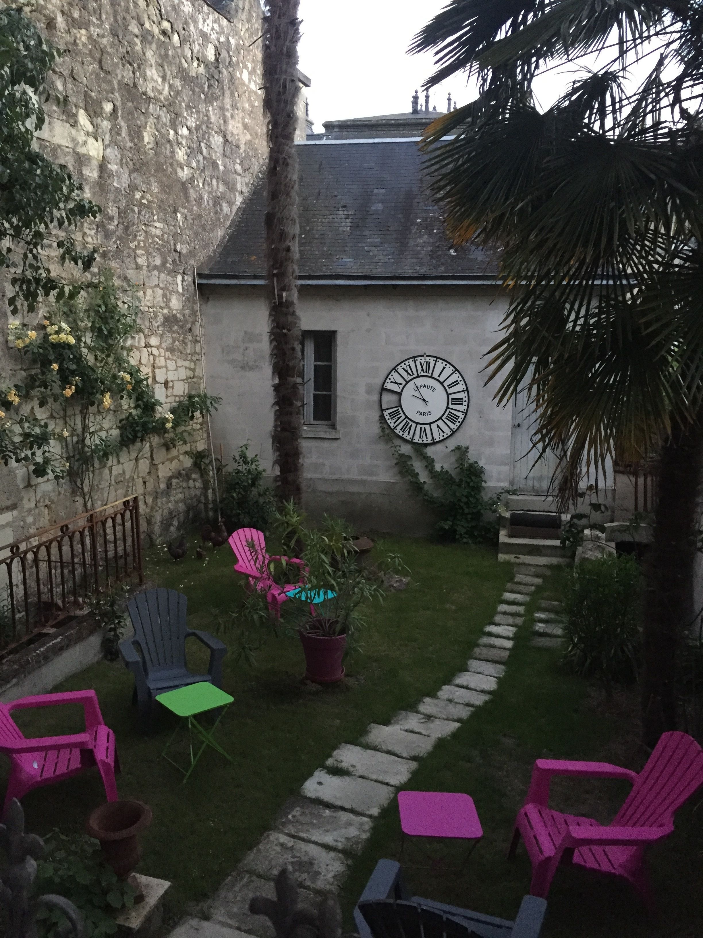 A courtyard with a stone wall, a clock, and outdoor seating.