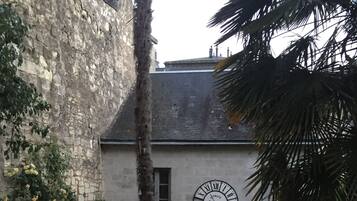 A courtyard with a stone wall, a clock, and outdoor seating.