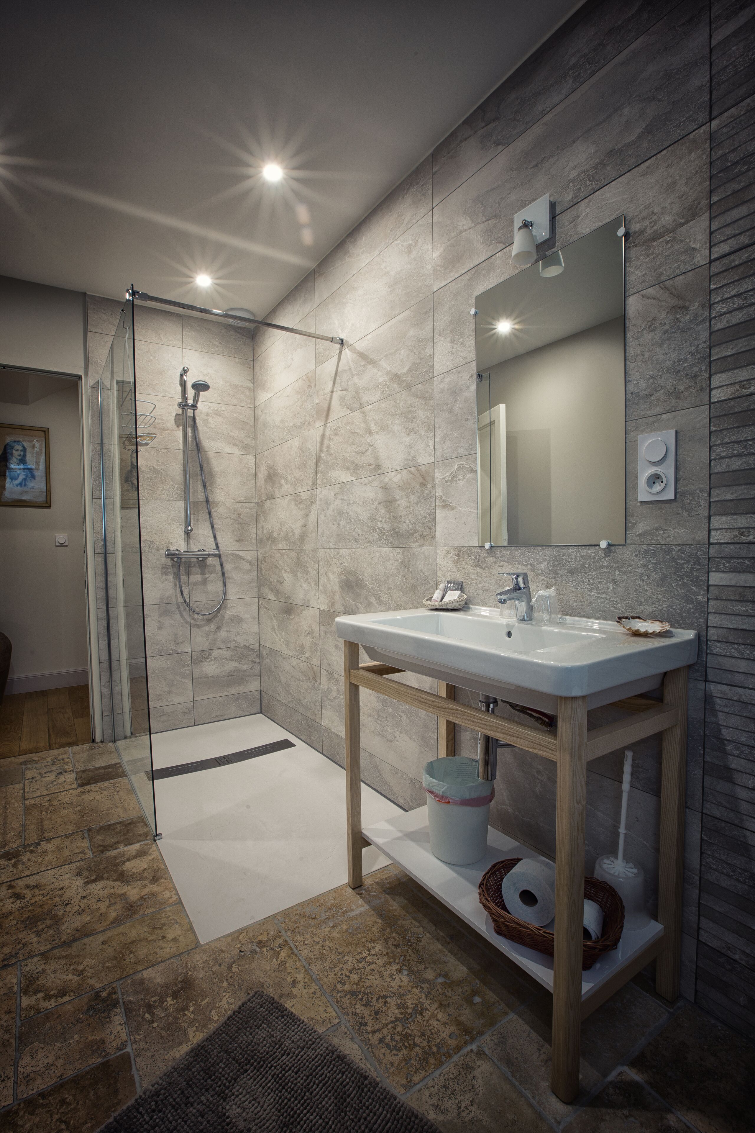 A modern bathroom with a glass-enclosed shower, a white sink, and a wooden vanity.