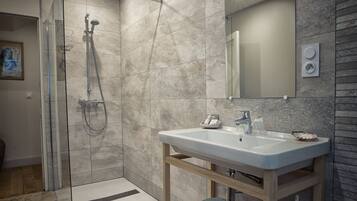 A modern bathroom with a glass-enclosed shower, a white sink, and a wooden vanity.