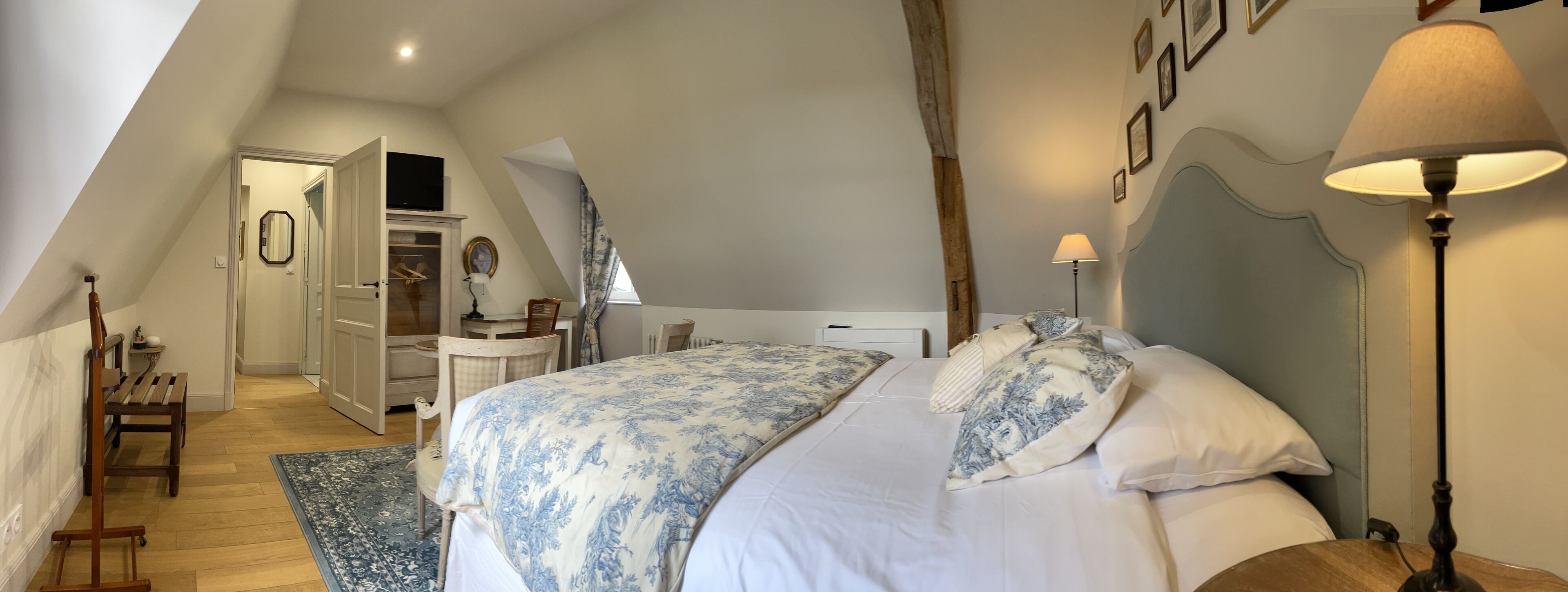 A bedroom with a large bed, a nightstand, a lamp, and a wardrobe.