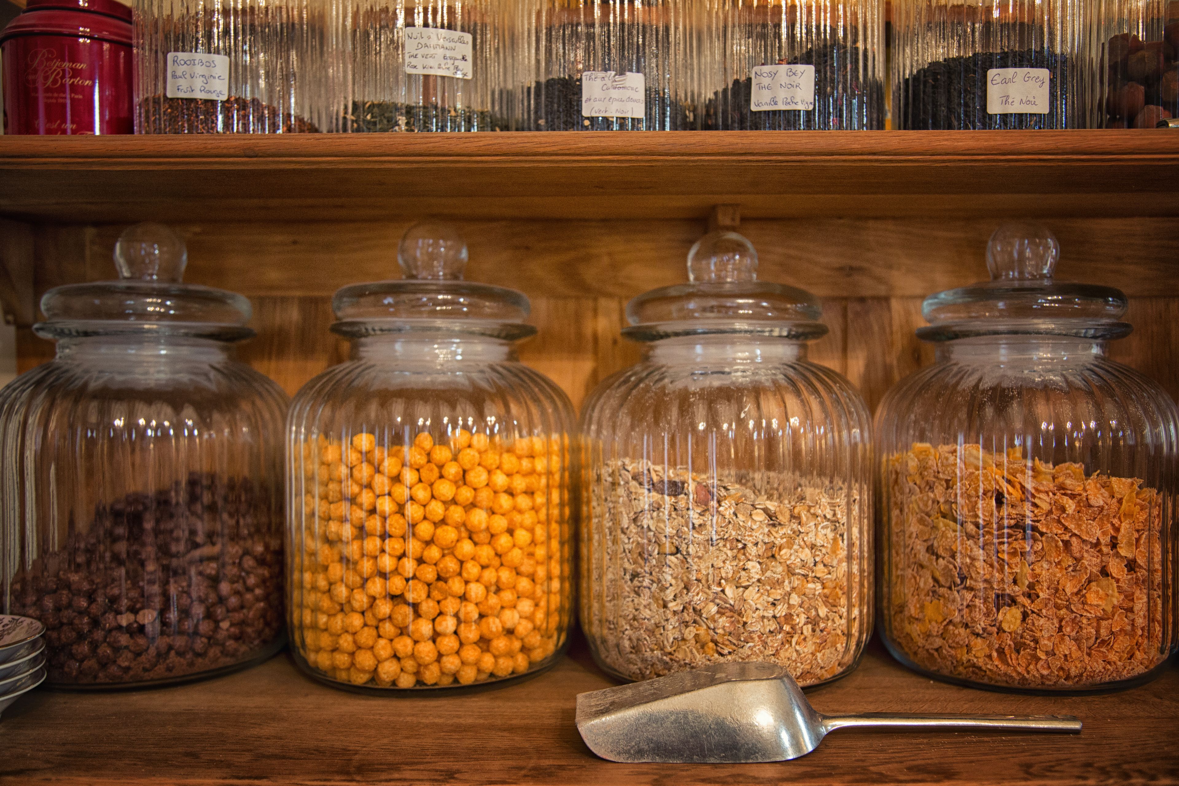 Four glass jars with different contents on a wooden shelf.