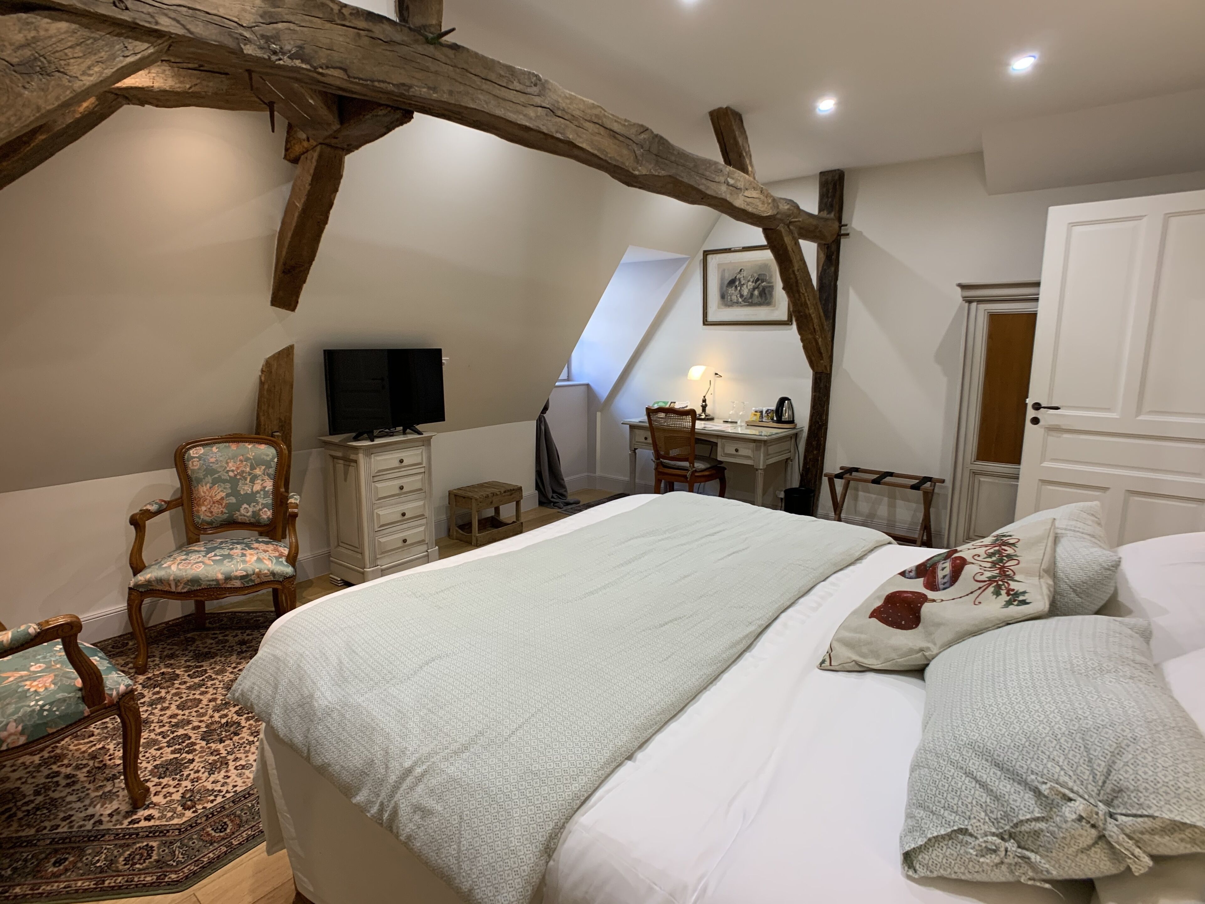 Ein Schlafzimmer mit einem großen Bett, einem Schreibtisch, einem Stuhl und einem Fernseher.