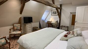 Ein Schlafzimmer mit einem großen Bett, einem Schreibtisch, einem Stuhl und einem Fernseher.
