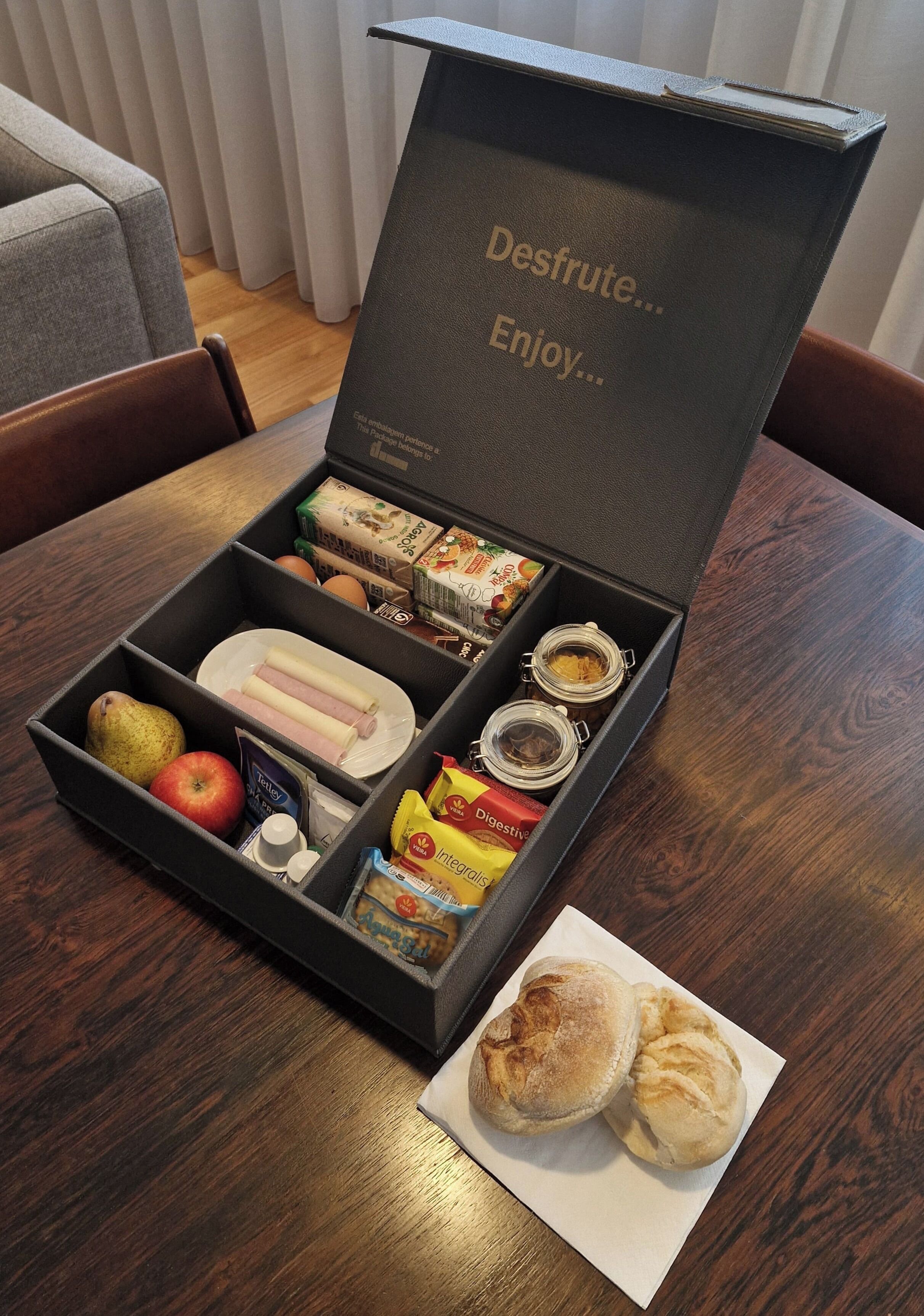 A meal box with compartments containing food items like bread, ham, cheese, and condiments.