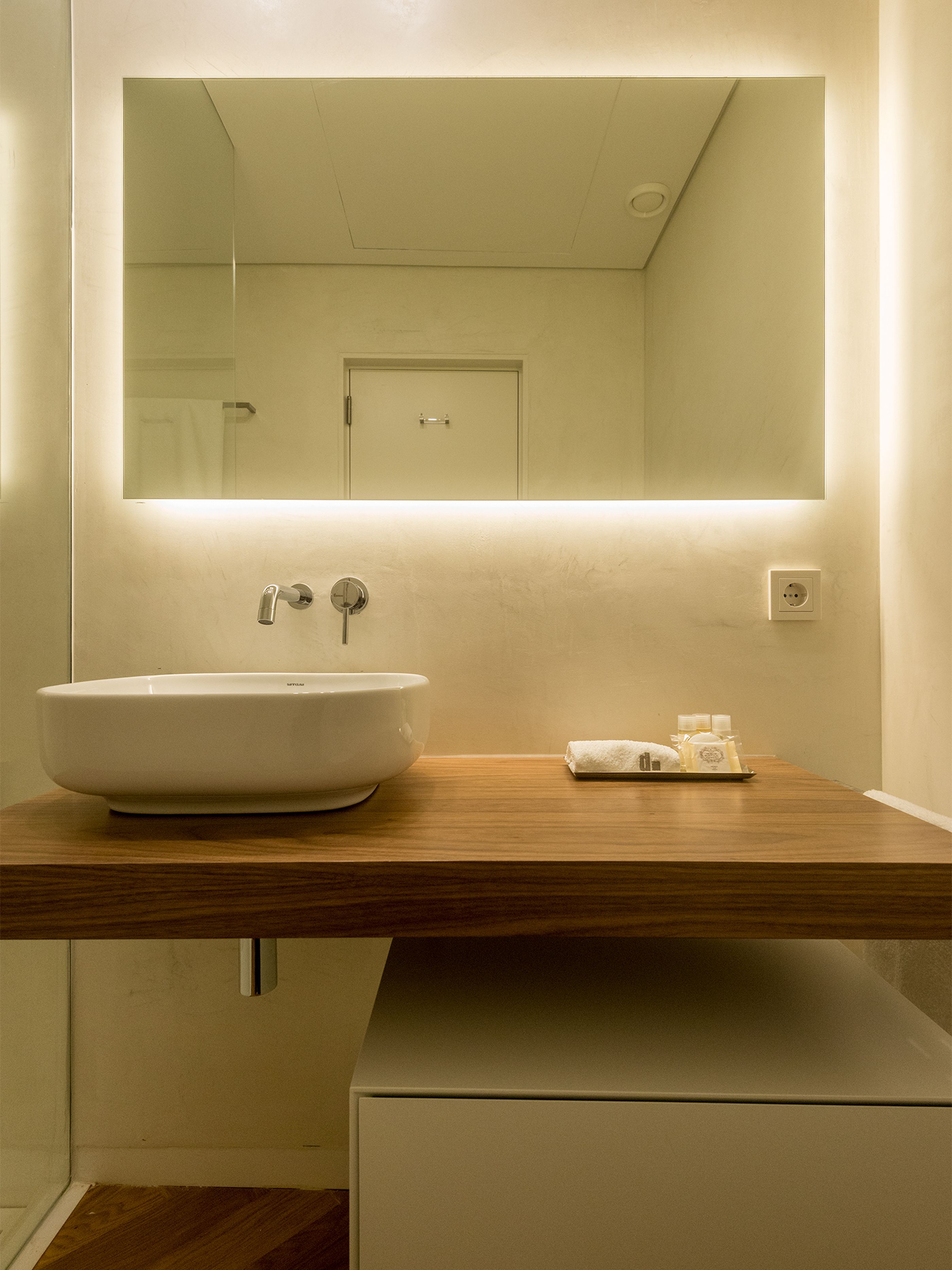 A bathroom with a large mirror, a white sink, and a wooden countertop.