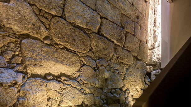 Una escalera con paredes de piedra y un accesorio de iluminación en la parte inferior.