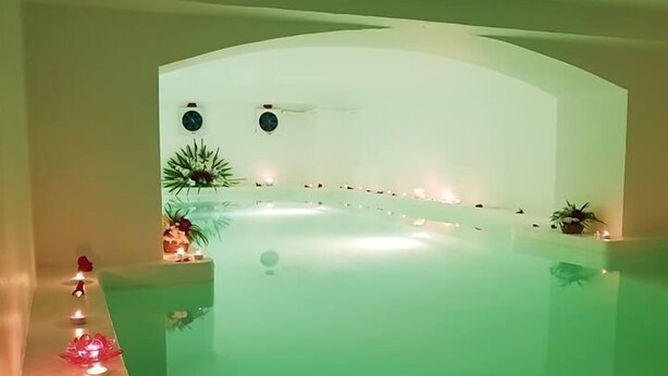 A spa pool with a curved edge, surrounded by candles and small plants. - Havana Resort (Antananarivo)