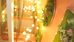 A modern interior with a string of spherical lights and a vertical garden wall. - Havana Resort (Antananarivo)