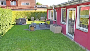 Ein rotes Haus mit einem Hinterhof und einer Terrasse, ausgestattet mit Gartenmöbeln und einem Whirlpool.