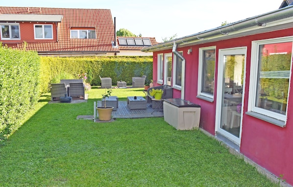 A red house with a backyard patio area featuring outdoor furniture and a hot tub.
