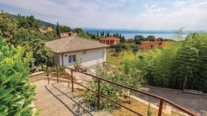 Una casa con tetto in tegole, circondata dal verde e vista mare.