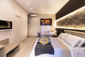 A modern hotel room with a large bed, a flat-screen TV mounted on the wall, a world map artwork, and a bedside table. - Starita Bed & pizza (Naples)